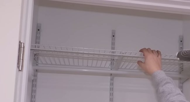 A person is opening the door of a closet to hang wire shelves