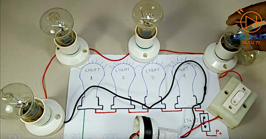 A person finishing up the series wiring for a light bulb with a switch