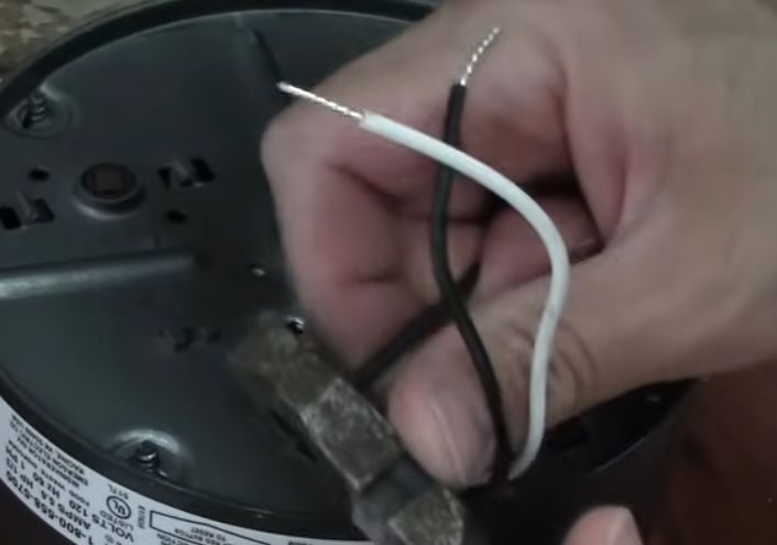 A person stripping the black and white wires