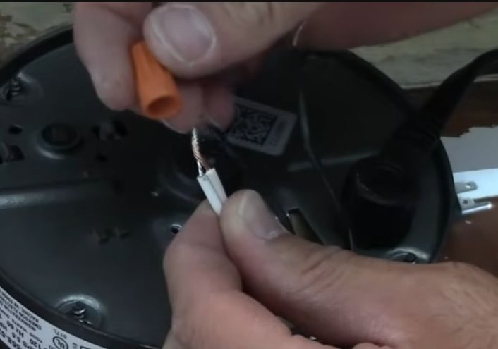 A person capping off a white stripped wires using wire nut