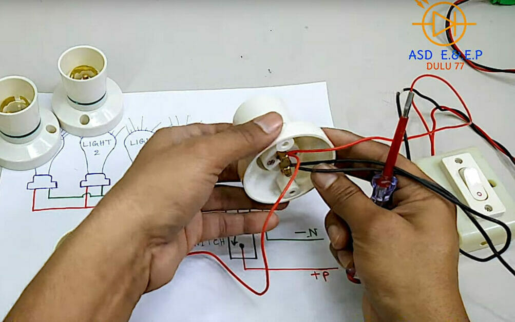 A person is working with electrical wires to wire multiple lights to one switch