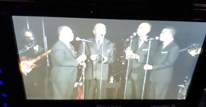 Group of 4 gentlemen singing with their standing microphones