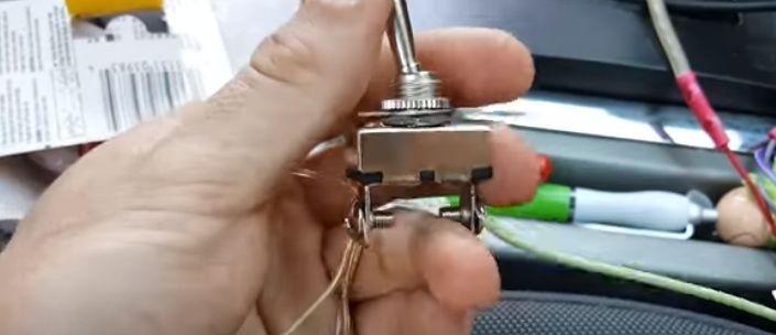 A person is holding a toggle switch