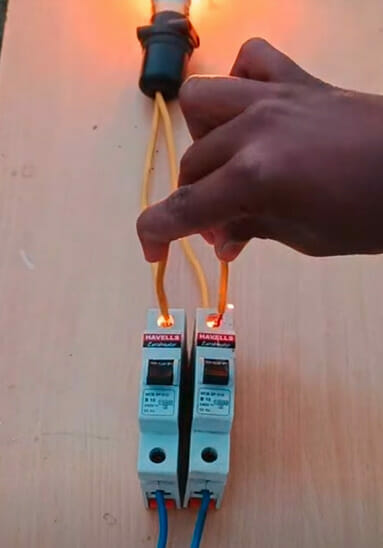 A person is connecting a wire of a light bulb to an electrical switch