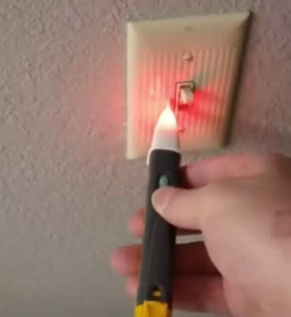 A person uses a voltage detector to ensure there is no power