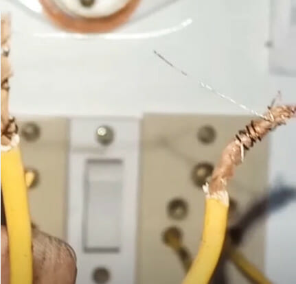 A person holding a yellow wire demonstrates the consequences of touching positive and negative wires