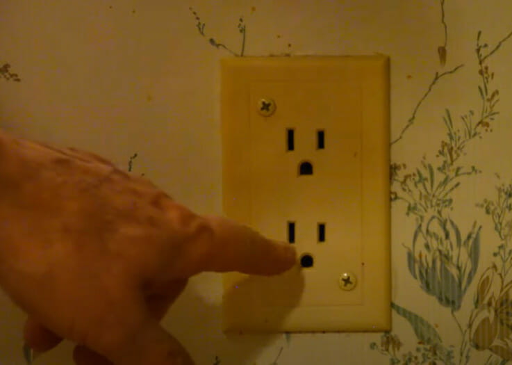 A person pointing at an outlet on a wall