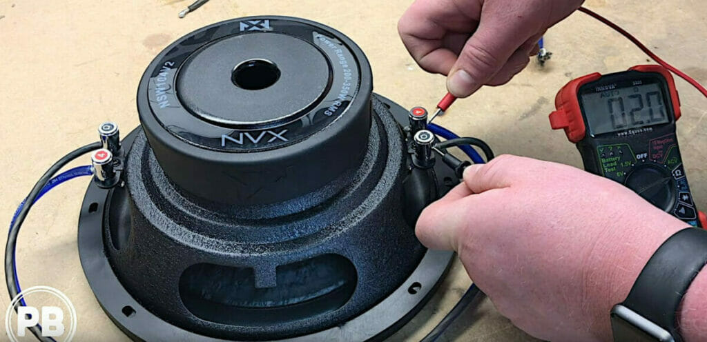 A person testing the NVX subwoofer with a multimeter