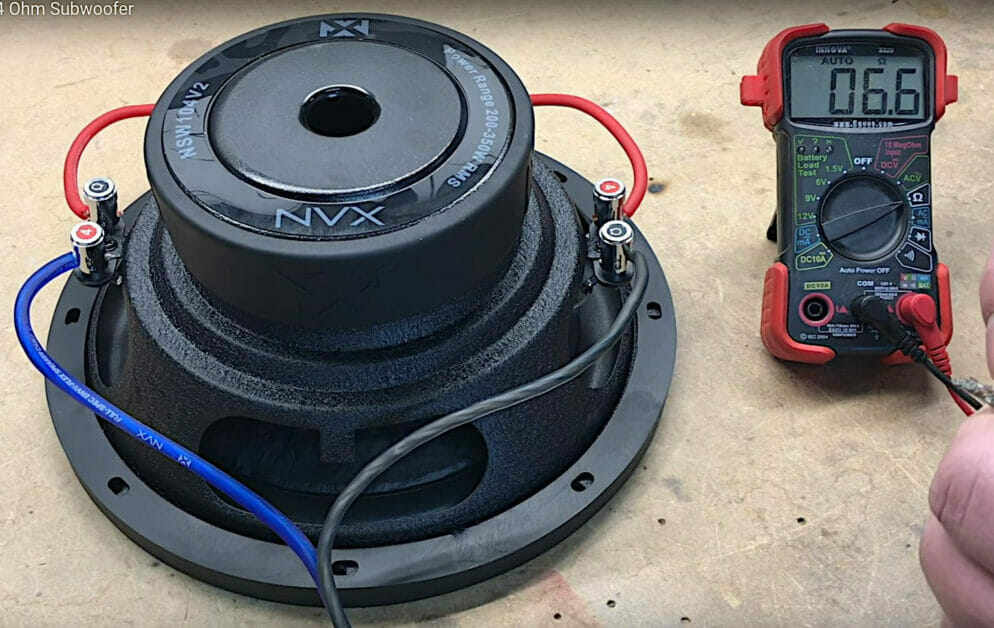 A wired 4-ohm DVC subwoofer besides a multimeter