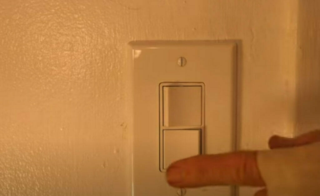 A person testing the double switch outlet on the wall