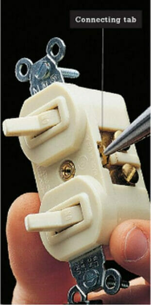 A person removing the connecting tab on the double switch