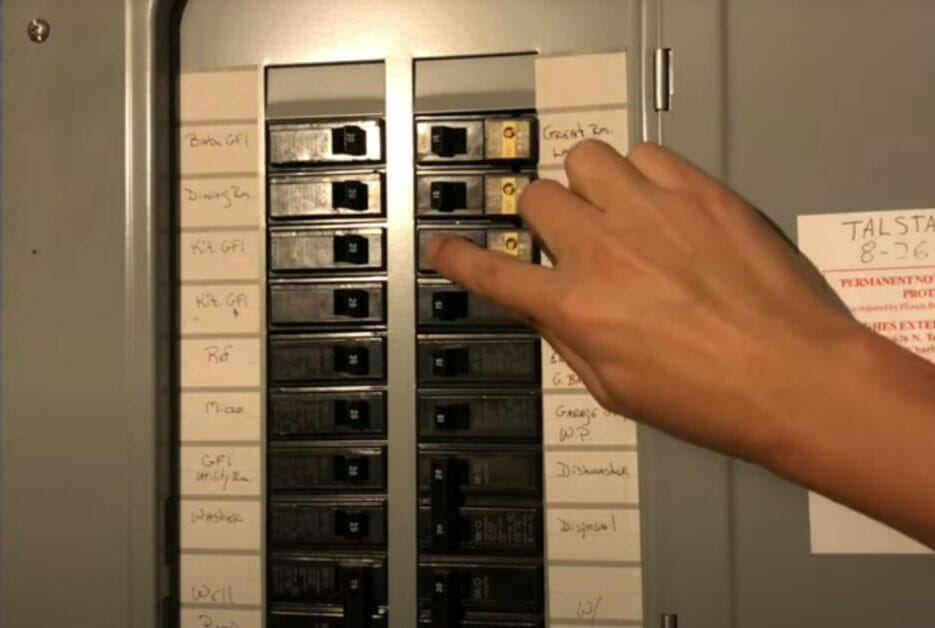 A person turning off a circuit breaker in a main electrical panel