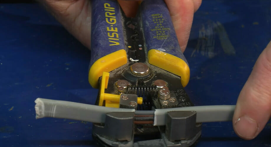A person is using a wire crimper to cut a wire for lighting