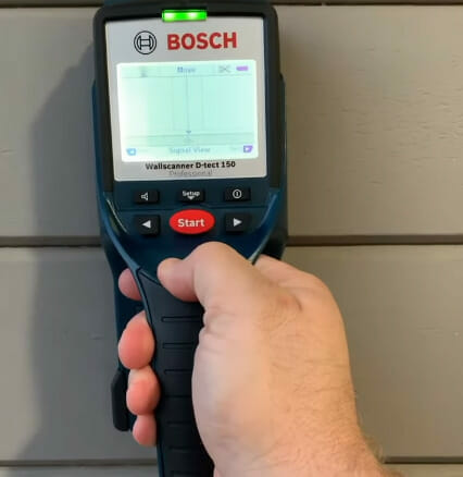 A person using a Bosch meter to measure the electrical wiring gauge for lighting
