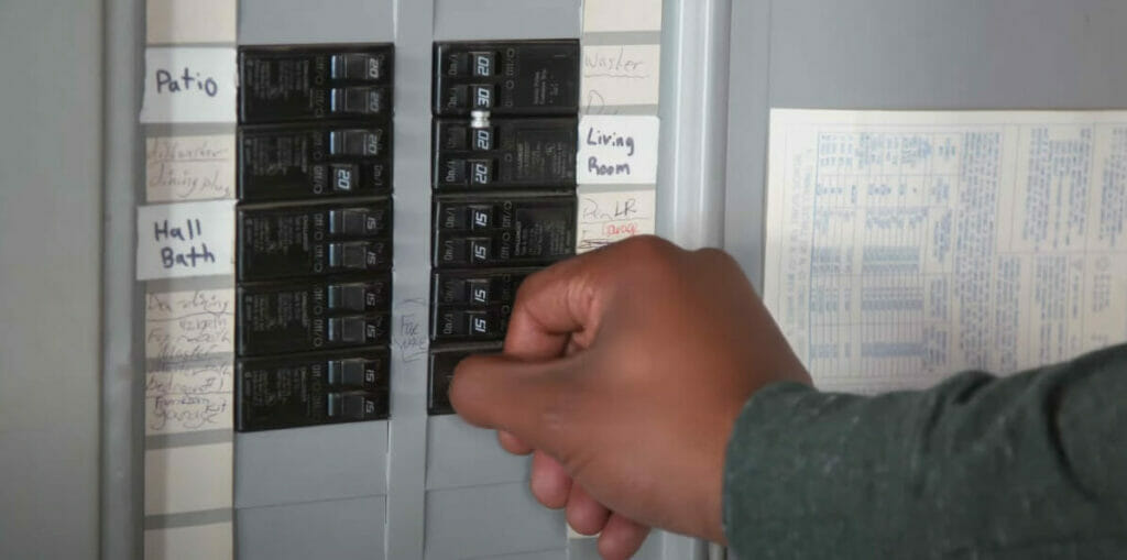 A person is turning on a breaker in a main circuit panel