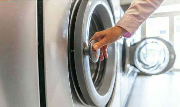 A person is pushing a button on a washing machine
