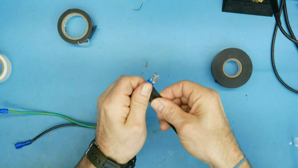 A man is taping a wire on a blue table