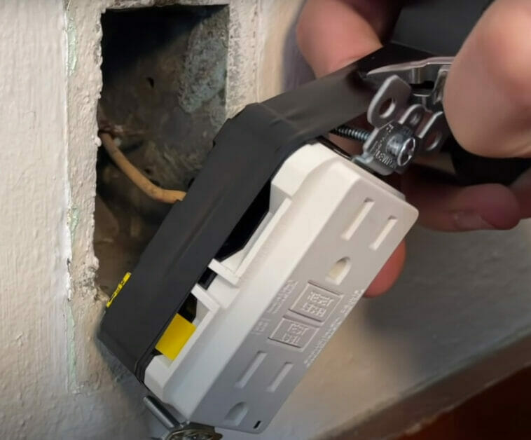A person working on a GFCI outlet on the wall