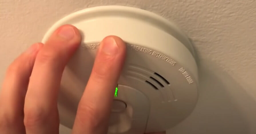 A person turning on the smoke detector at the ceiling