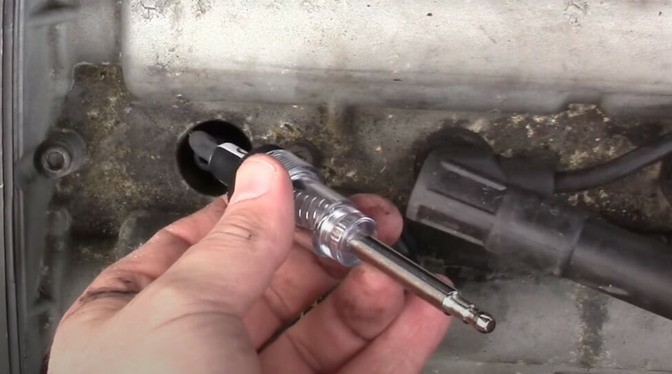A person's left hand holding a spark plug