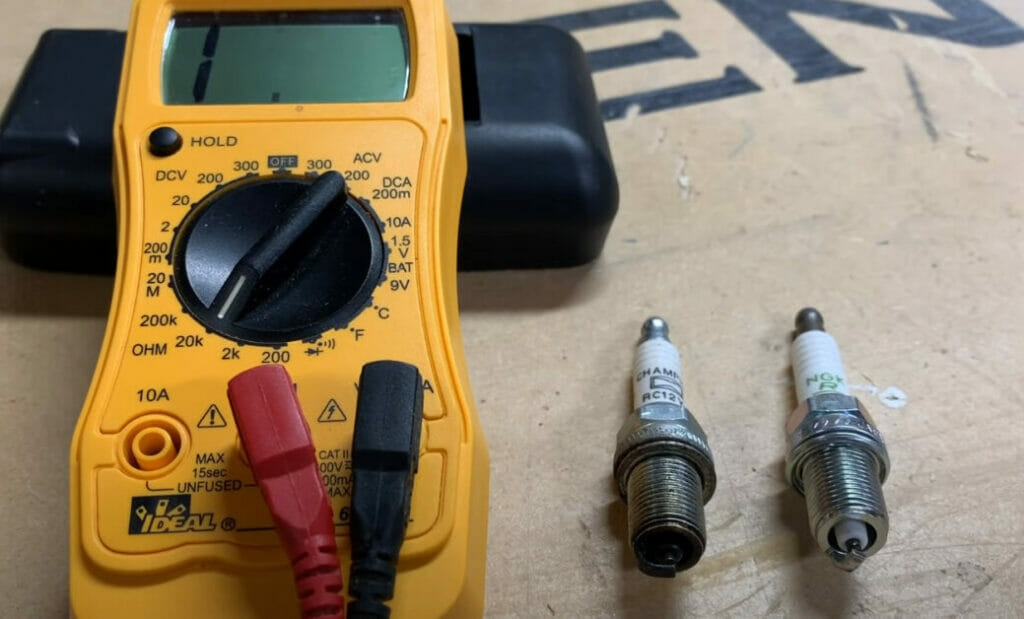 A multimeter and two spark plugs on the table