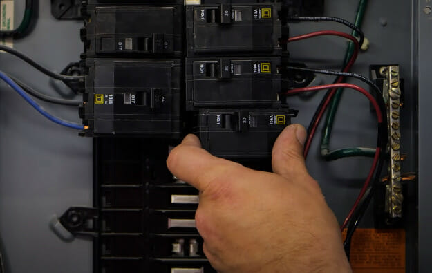 A person inserting a circuit breaker into the main circuit panel