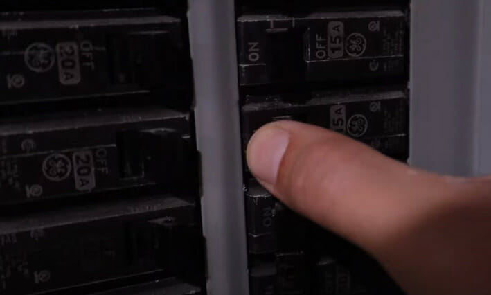 A person turning off the breaker on a main circuit panel