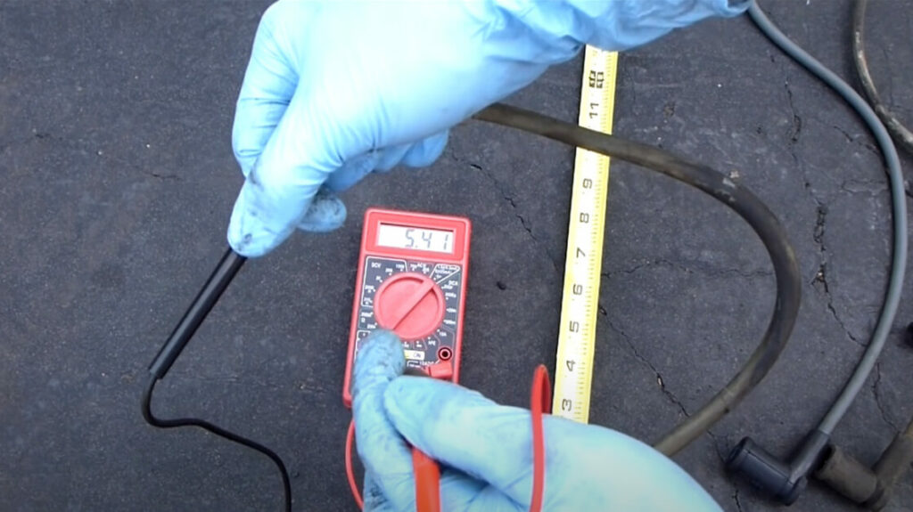 A person wearing blue gloves holding a multimeter