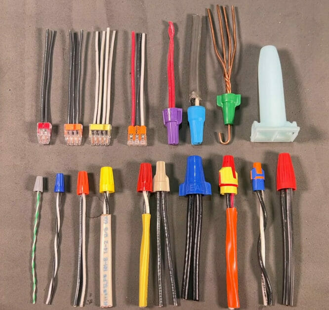 A variety of wires and connectors and wire nuts are laid out on a table 
