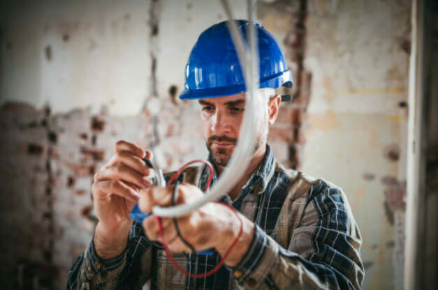 A man in a blue safety hat working with wires