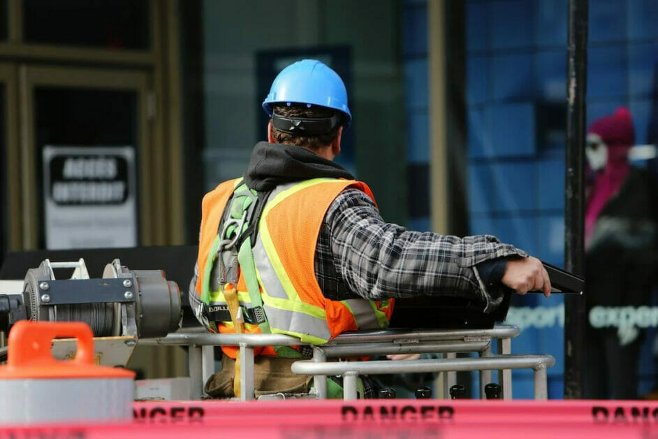 A construction worker wearing a hard hat and safety vest standing outside a building