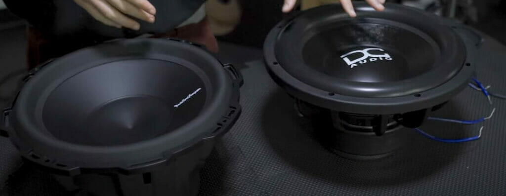A person is checking a pair of car subwoofers