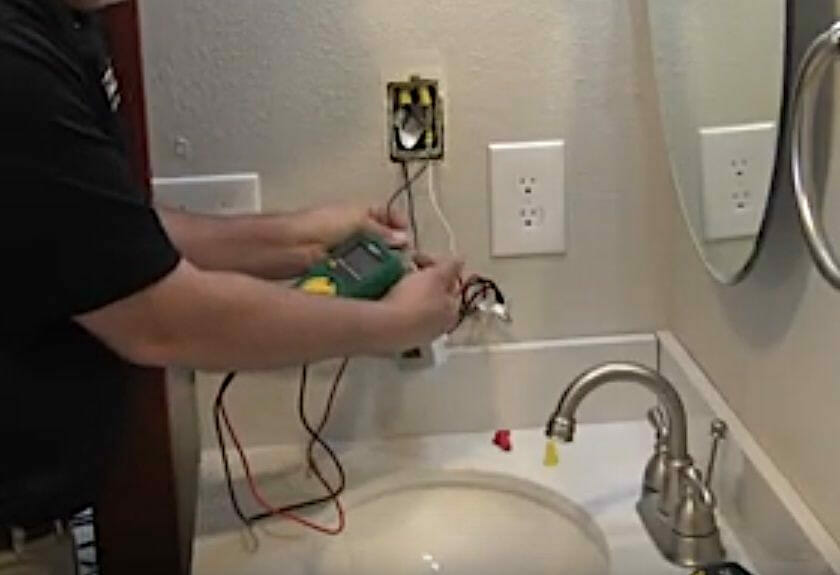 A person conducting a resistance test on the thermostat wiring