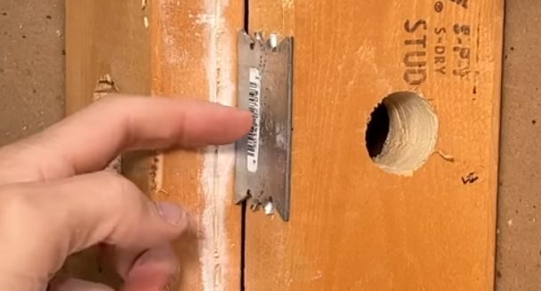 A person putting metal plate to protect the stud