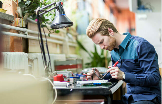 A man soldering a board on his desk