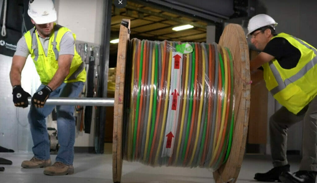 Two men working on a big roll of SIMpull wires