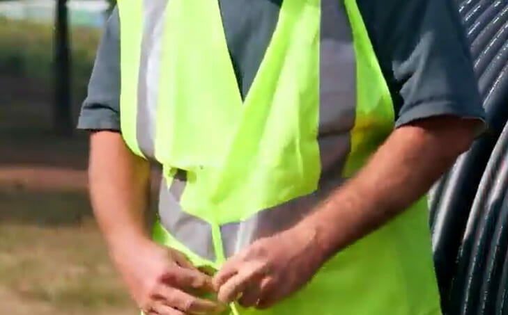 A man wearing an neon and grey safety body vest