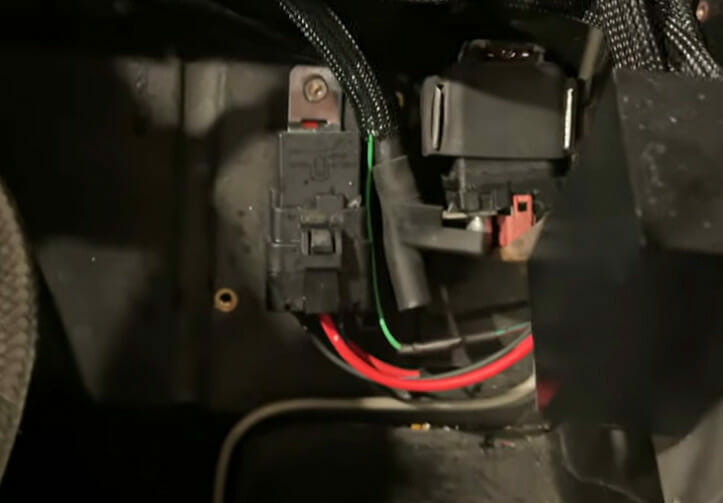 A car's fuse box with wires in it