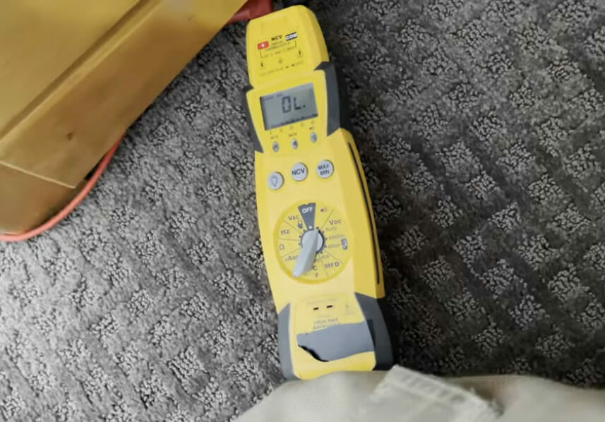 A yellow voltmeter on the carpeted ground
