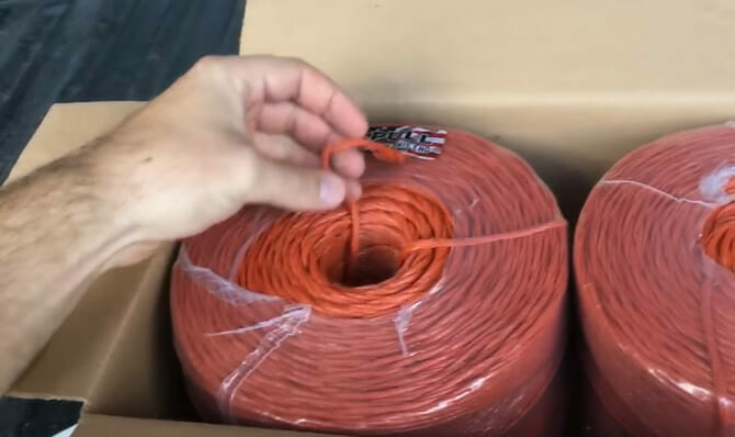 A person is packing a roll of an orange baling twine