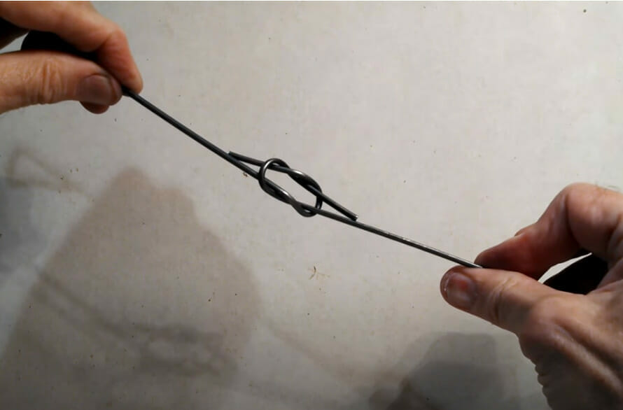 A pair of hands demonstrating the use of baling wire