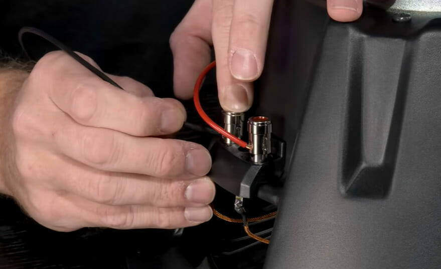 A person is inserting the black wire into a dual voice coil subs