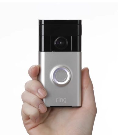 A woman's hand holding a RING doorbell