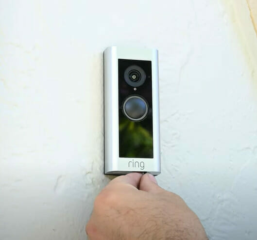 A person testing a Ring doorbell on the wall