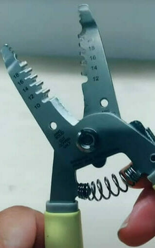 A person is holding a wire stripper tool