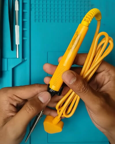 A person is holding a yellow soldering iron