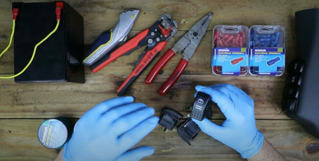 A person in a blue gloves preparing the tools for wiring a rocker switch