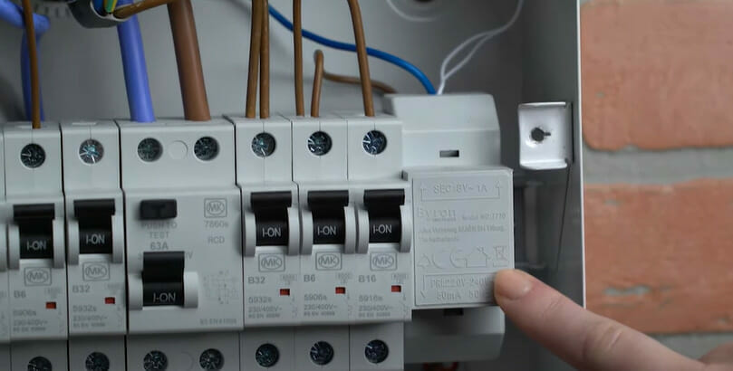 A person pointing at a circuit panel with circuit breakers