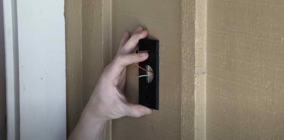 A person wiring a doorbell on the wall
