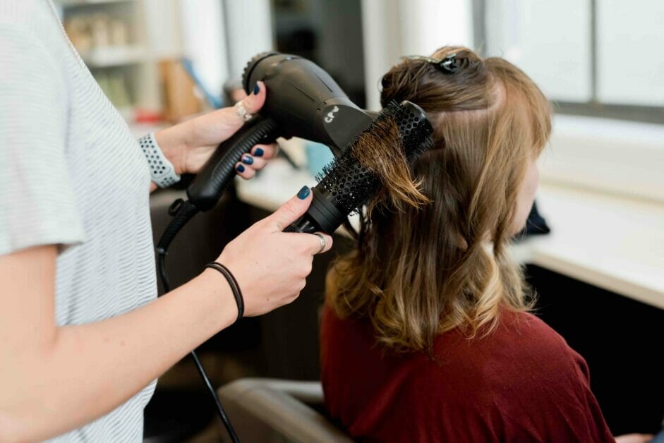 Woman drying other woman's hair with a hair dryer
